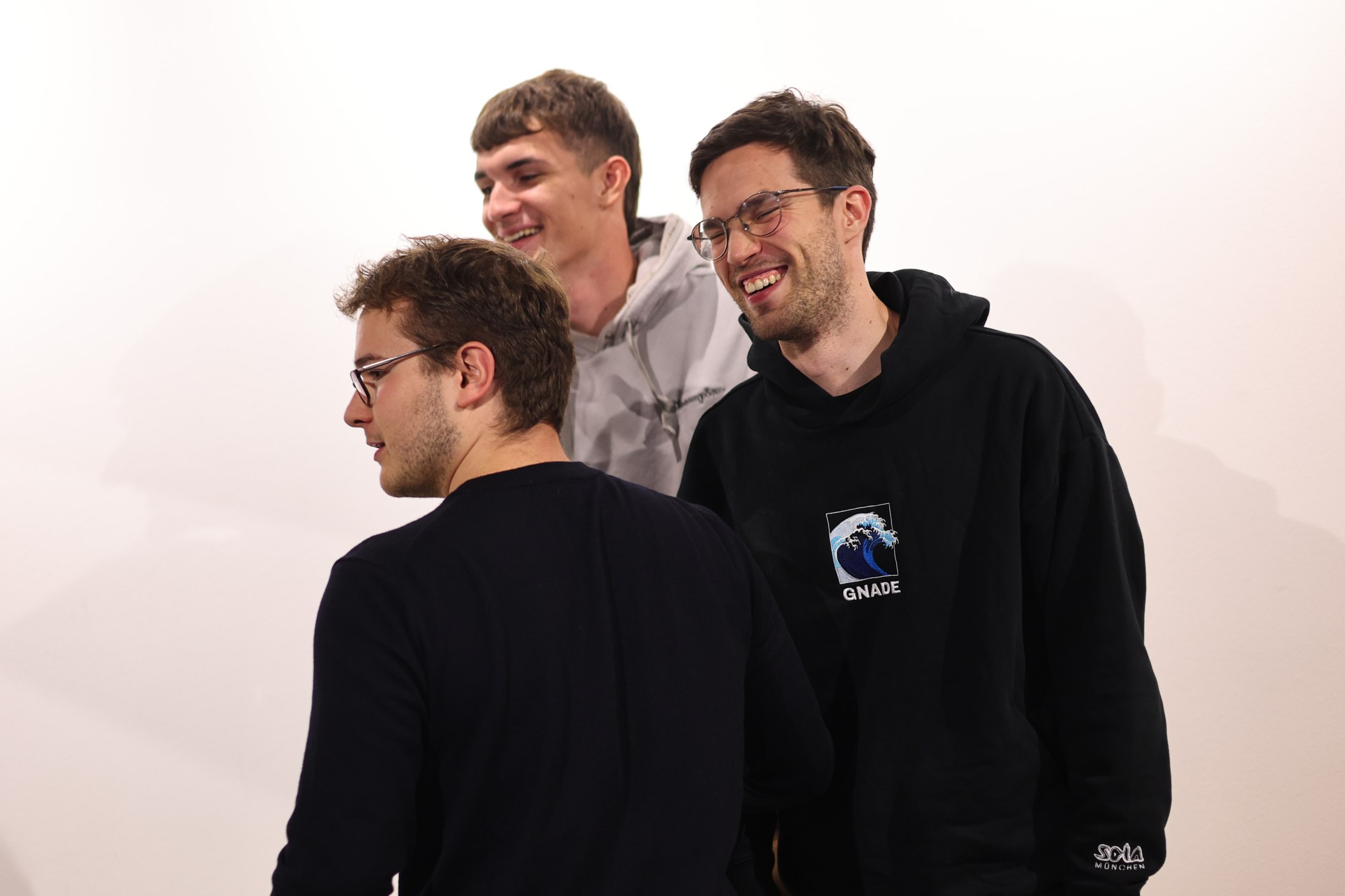 Drei junge Männer lachen miteinander.