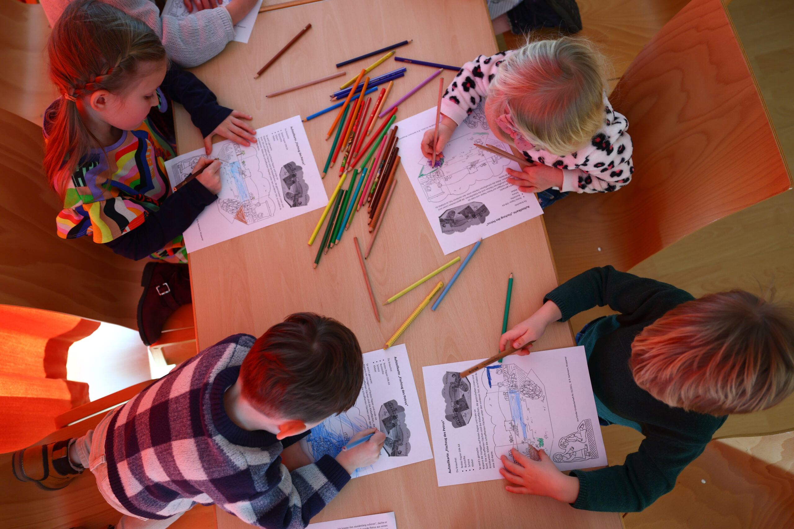 Kinder malen gemeinsam an einem Tisch.